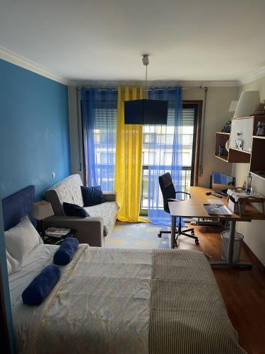 a bedroom with a bed and a living room with a desk at Quarto junto ao mar in Matosinhos