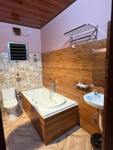 a bathroom with a tub and a sink and a toilet at Dev Murti Eco Resort in Chālsa Mahābāri