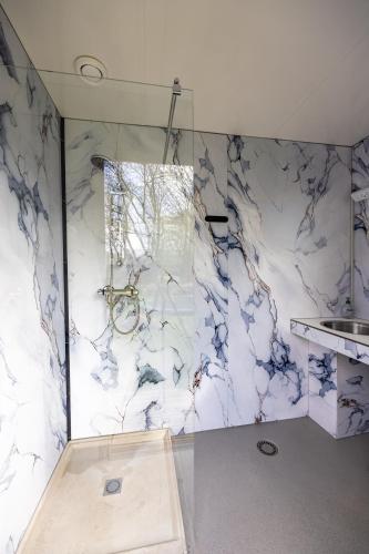a bathroom with a shower with a marble wall at Back to Basic in Zwaanshoek