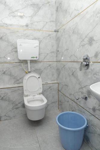 a bathroom with a toilet and a blue bucket at Hotel Midnight Lodging & Boarding in Panvel