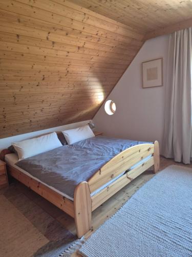 a bed in a room with a wooden ceiling at Singer-Hof in Krumpendorf am Wörthersee