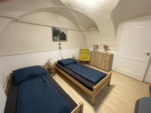 a bedroom with two beds and a yellow chair at Takács Vendégház 2 in Sopron