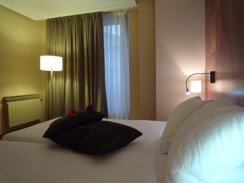 a bedroom with a bed with two pillows and a window at Hotel Picos de Europa in Arenas de Cabrales