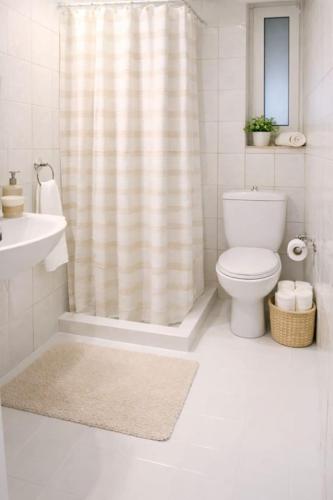 a bathroom with a shower curtain and a toilet at Yviome Rhodes Central Escape in Rhodes Town