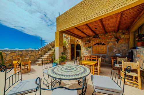 a patio with a table and chairs and a stone wall at Berber Surf House in Tamraght Ouzdar