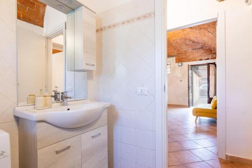 a white bathroom with a sink and a mirror at Windrose Cottage di Gio in Pisa