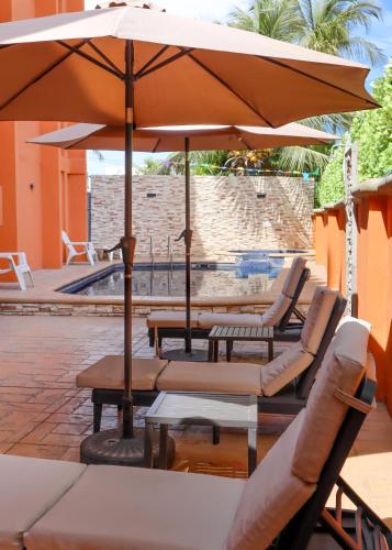 a group of chairs and an umbrella on a patio at Hotel Boutique Plaza Doradas in San José del Cabo