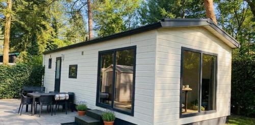 a small white shed with a table and chairs at Veluwe Droom Chalet in Hoenderloo