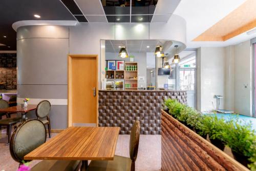 a restaurant with wooden tables and chairs and a counter at Eurotraveller Hotel - Premier - Harrow in Harrow