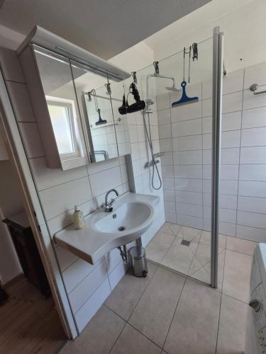 a white bathroom with a sink and a shower at Villa Nusswald in Krumpendorf am Wörthersee