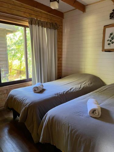 two beds in a bedroom with towels on them at Ruca del Fuy in Panguipulli