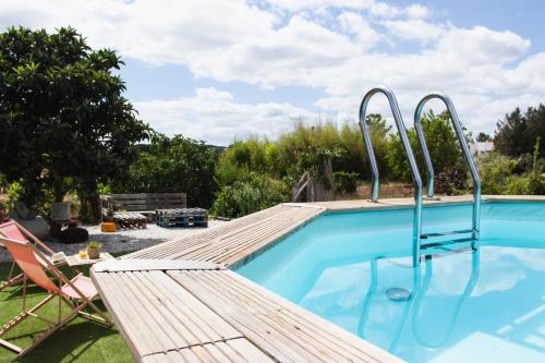a swimming pool with a wooden deck and a chair next to it at Chitaka's Organic Farmhouse in Ribatejo in Santo Estêvão