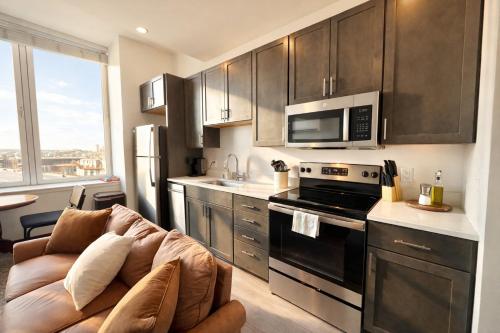 a living room with a couch in a kitchen with a microwave at Deer District Studio Apt - One Block from Fiserv and Baird in Milwaukee