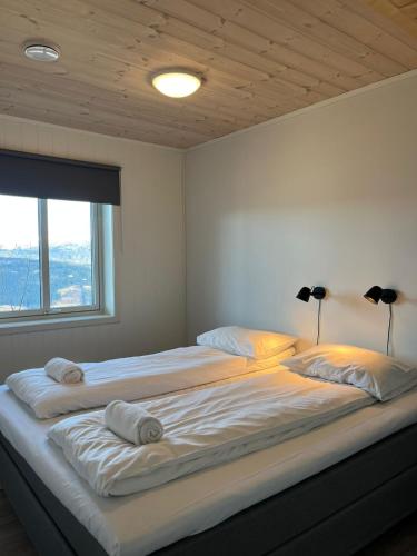 two beds in a bedroom with a large window at Affordable Luxury Sauna Chalet - River Views in Vossevangen
