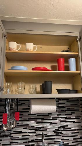 a kitchen shelf with dishes and cups on it at Cozy Haven your home away from home in Hollywood