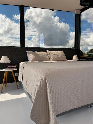 a bedroom with a white bed with a large window at Residencial Canto dos Passarinhos - Loft e Apartamentos in Alto Paraíso de Goiás