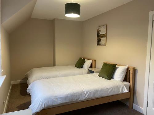a room with two beds with white sheets and green pillows at West Highland Hideaway in Kinlochleven