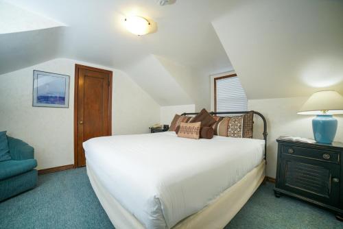 a bedroom with a white bed and a blue chair at Ecola Creek Lodge in Cannon Beach
