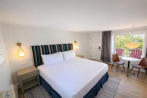 a hotel room with a bed and a table and chairs at The Foxberry - A Digital Concierge Guesthouse in Provincetown