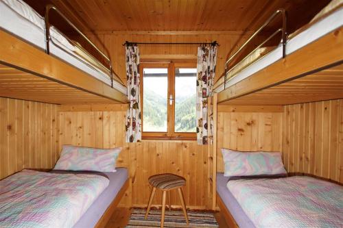 two beds in a wooden room with a window at Chalet Valuga in Kaisers