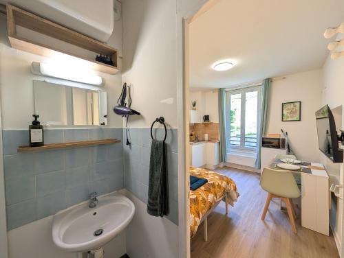 a bathroom with a sink and a bed in a room at Le Studio Évasion Tropicale in Quimper