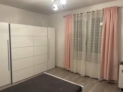 a room with white cabinets and pink curtains at Jak w domu in Słupsk