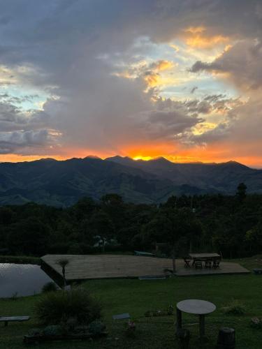 a sunset over the mountains with a picnic table at Chalé canaã in Passa Quatro