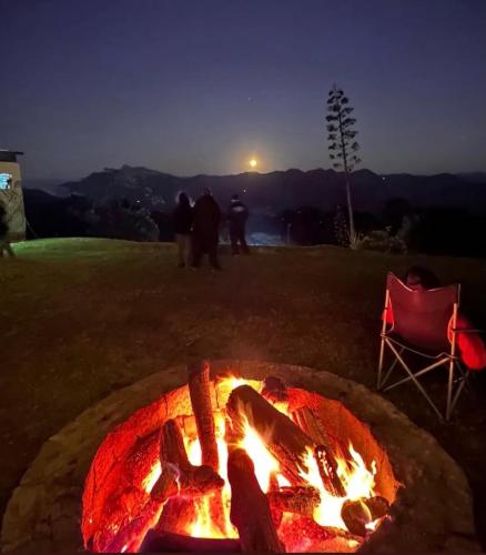 a fire pit with people standing around it at night at Chalé canaã in Passa Quatro