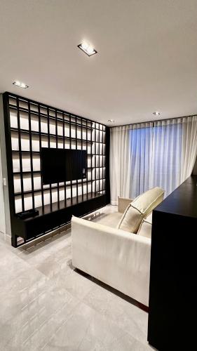a living room with a large white couch and a tv at Apartamento de Luxo 2 Quartos, Brasília - Get Park Sul - com Garagem in Brasília