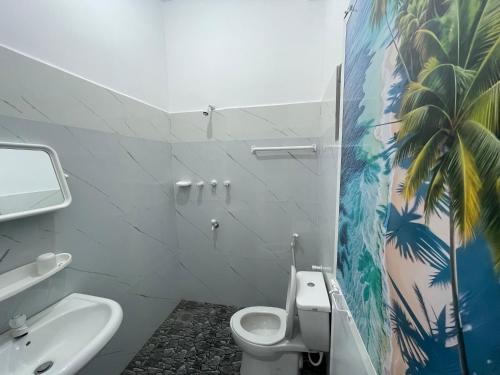 a bathroom with a white toilet and a palm tree mural at LA PRINCE HOTEL and HOSTEL in Trincomalee