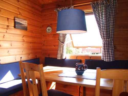 a dining room with a table and a blue lamp at dieSeeSucht - Lodge am Fjord in Westerholz