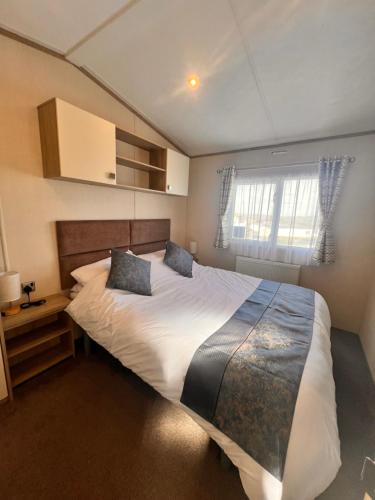 a bedroom with a large bed and a window at Swanage Luxury Caravan - Stunning sea views, Large decking area, Free EE WIFI, Sleeps 6, Pet Friendly on Swanage Bay View Holiday Park in Swanage