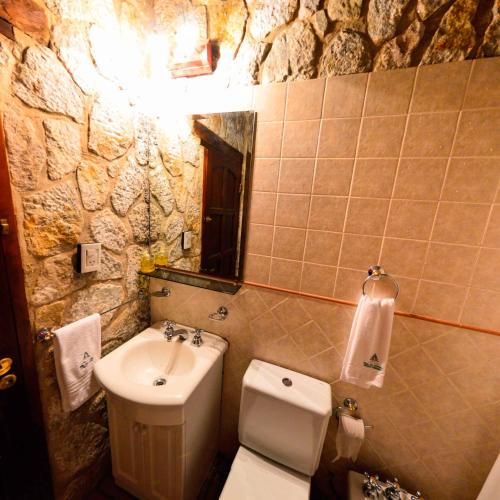 a bathroom with a sink and a toilet and a mirror at Pinar del Arroyito in Villa General Belgrano