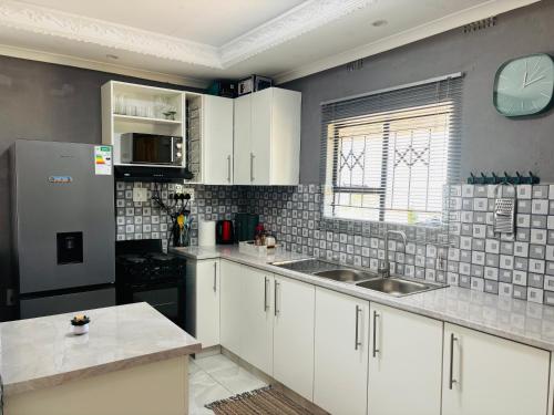 a kitchen with white cabinets and a clock on the wall at The Valley View Nest in Ezulwini