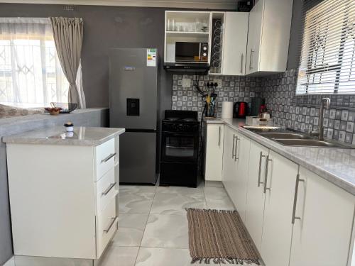 a kitchen with white cabinets and a black refrigerator at The Valley View Nest in Ezulwini
