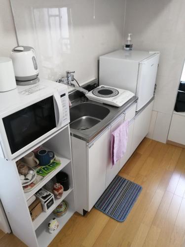 a small kitchen with a sink and a microwave at Tokyo downtown牡丹莊 in Tokyo