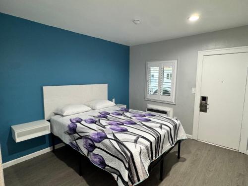 a bedroom with a bed with a blue wall at Angel's Motel near Anaheim in Orange