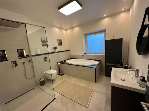 a bathroom with a shower and a tub and a sink at Auszeit nahe Freizeitpark in Grethem