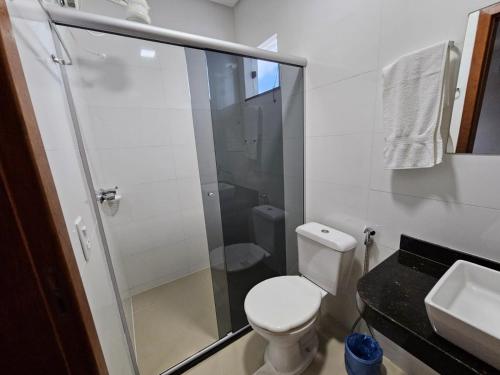 a bathroom with a toilet and a shower and a sink at Apto Garden Taperapuan 2 quartos com suíte in Porto Seguro