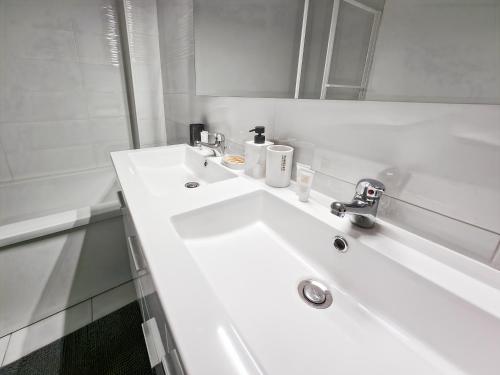a white bathroom with a sink and a mirror at Maison Familiale, Jardin Privé, Proche Disneyland in Coutevroult