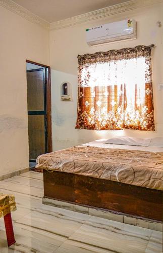 a bedroom with a bed and a window with a curtain at Hotel GK Lodging & Boarding in Khāpri