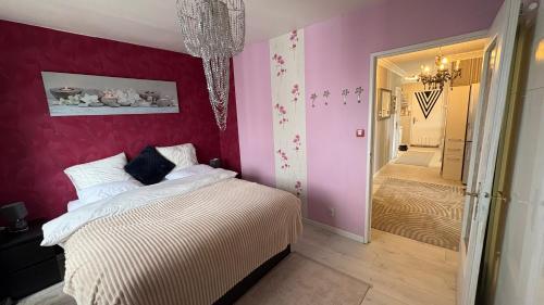 a bedroom with a white bed and a pink wall at Bellevue in Colmar