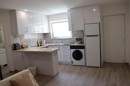 a kitchen with white cabinets and a sink and a dishwasher at Lugar de São Braz in Alter do Chão
