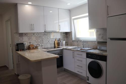 a kitchen with white cabinets and a sink and a dishwasher at Lugar de São Braz in Alter do Chão