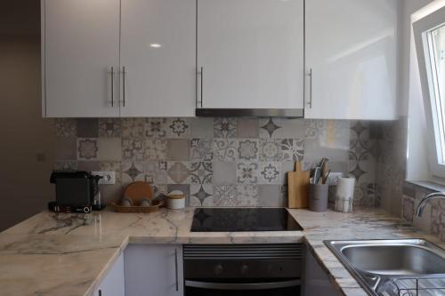 a kitchen with white cabinets and a sink at Lugar de São Braz in Alter do Chão