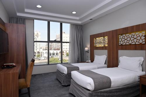 a hotel room with two beds and a desk and a window at Salsbil Almasi Hotel in Medina