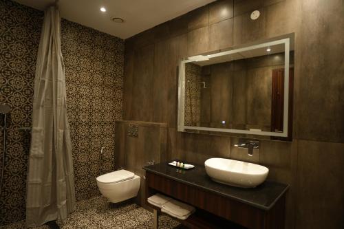 a bathroom with a sink and a toilet and a mirror at ACR Luxury Hotel in Mohali