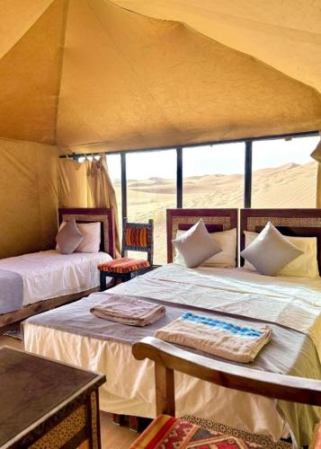 a bedroom with two beds in a tent at Elite Sahara Desert Camp in Merzouga