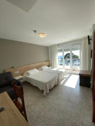 a hotel room with two beds and a couch at Hotel Riveiro in Sanxenxo