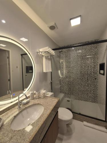 a bathroom with a sink and a toilet and a mirror at Gran Lençóis Flat Barreirinhas Caburé-209 com Quarto Deluxe Cama Queen Size in Barreirinhas